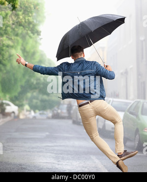 Man dancing with umbrella in rainy street Stock Photo