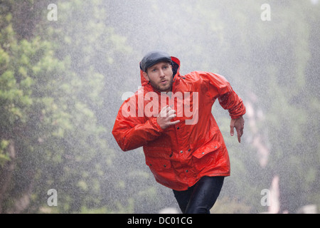Man in raincoat running in rain Stock Photo