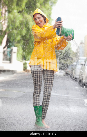 Portrait of enthusiastic woman emptying boot in rain Stock Photo