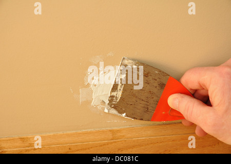 Putty Knife with filler / Pollyfilla / grout / spackling paste repairing a hole in the wall Stock Photo