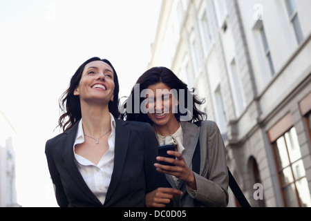Happy businesswomen text messaging with cell phone Stock Photo