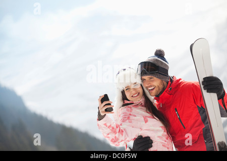 Happy couple with skis taking self-portrait with camera phone Stock Photo