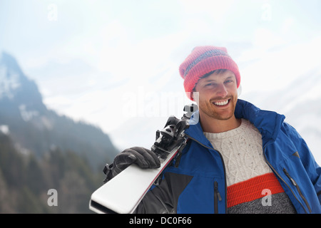 Portrait of smiling man holding skis Stock Photo