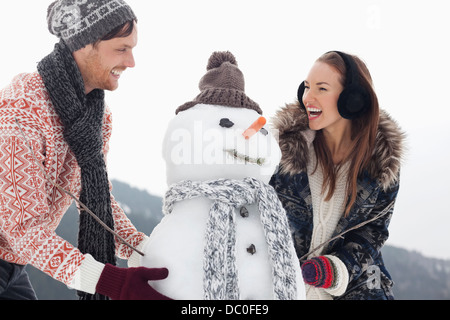 Happy couple making snowman Stock Photo