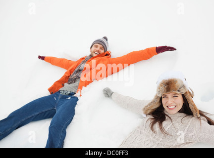 Portrait of happy couple making snow angels Stock Photo