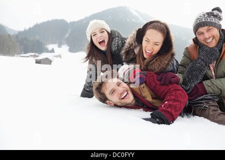 Playful friends laying in snowy field Stock Photo