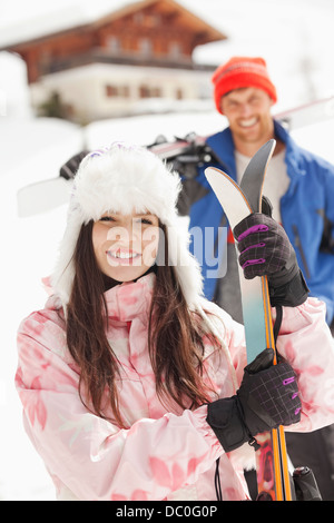 Portrait of smiling couple with skis outside cabin Stock Photo