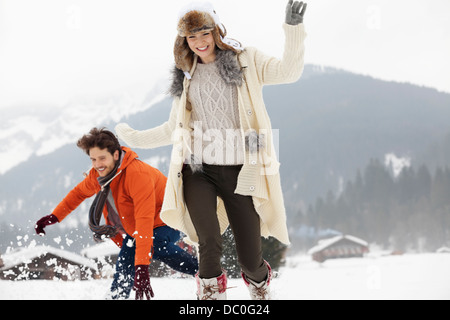 Playful couple running in snowy field Stock Photo