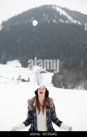 Snowball falling above enthusiastic woman in field Stock Photo