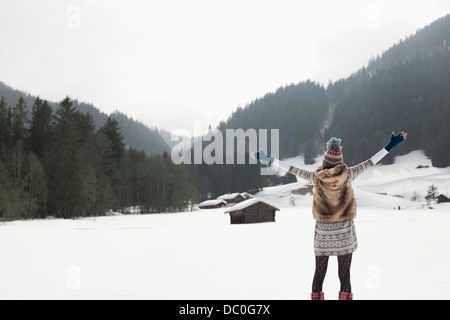 Carefree woman with arms outstretched in snowy field Stock Photo