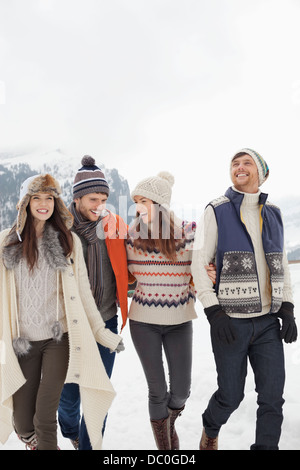 Happy friends walking in snowy field Stock Photo