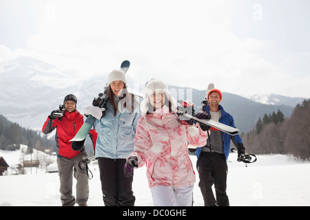 Enthusiastic friends with skis in snowy field Stock Photo