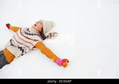 Enthusiastic woman making snow angel Stock Photo