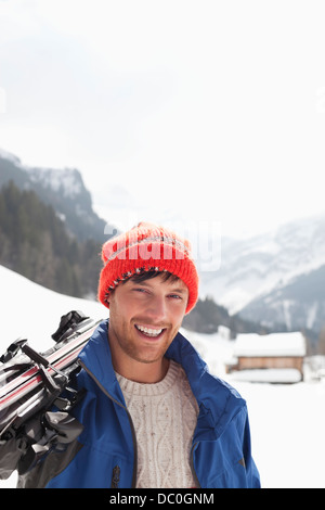 Close up portrait of smiling man carrying skis in snowy field Stock Photo