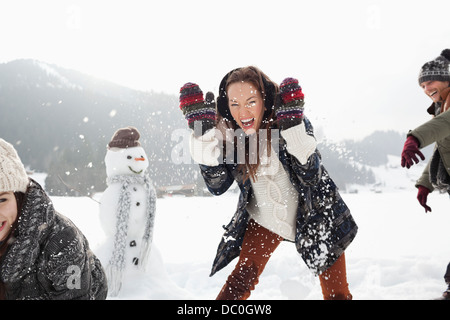 Enthusiastic friends enjoying snowball fight in field Stock Photo