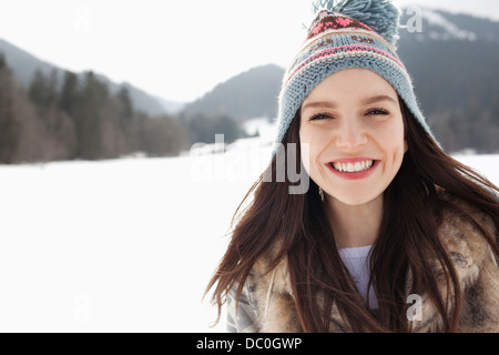 Close up portrait of happy woman wearing knit hat in snowy field Stock Photo