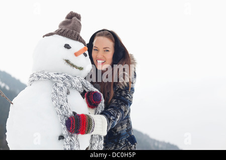 Portrait of happy woman hugging snowman Stock Photo
