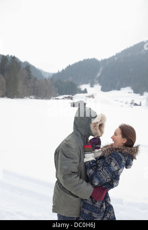Happy couple hugging in snowy field Stock Photo