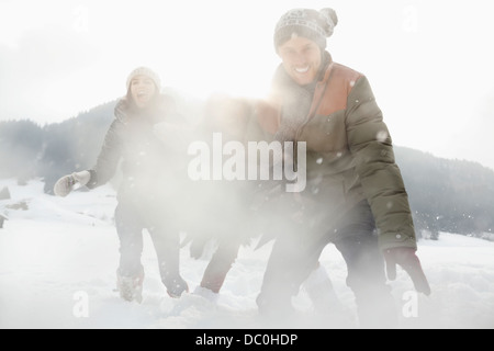 Portrait of playful friends enjoying snowball fight in field Stock Photo