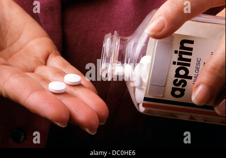 1990s FEMALE HAND TAKING TWO ASPIRIN TABLETS FROM BOTTLE Stock Photo