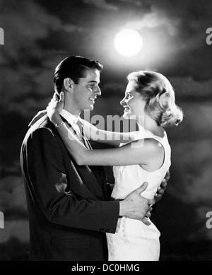 1960s YOUNG COUPLE EMBRACING IN MOONLIGHT Stock Photo