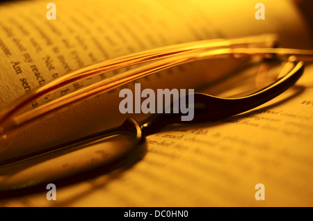 Reading glasses resting on an open book Stock Photo