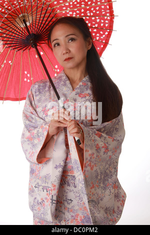 Japanese Lady Wearing a Pink and Lilac Patterned Kimono and Holding a Red Sun Shade.