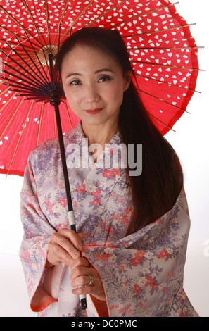 Japanese Lady Wearing a Pink and Lilac Patterned Kimono and Holding a Red Sun Shade.