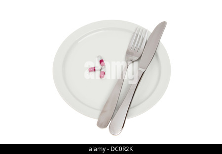 Pills with a knife and fork on a plate isolated against white Stock Photo