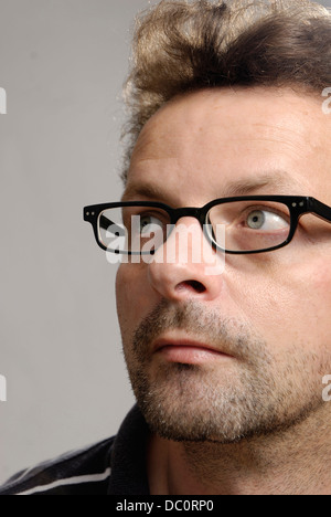 A man with glasses, a blue-white polo shirt and unshaven Stock Photo