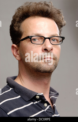 A man with glasses, a blue-white polo shirt and unshaven Stock Photo