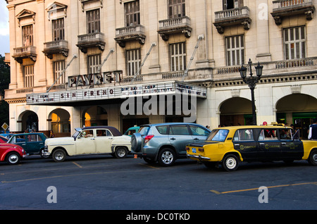 Central Havana 19th century movie theater showing 'Premium Rush', old car taxis parked in front. Stock Photo