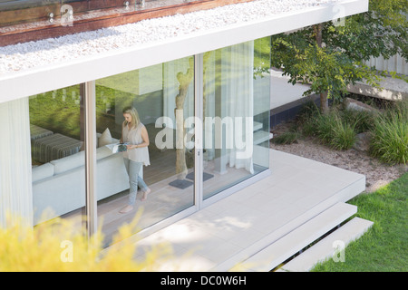 Woman walking along window inside house Stock Photo