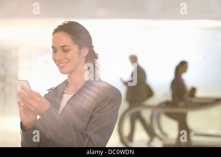 Smiling businesswoman text messaging with cell phone Stock Photo