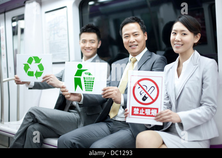 Business persons holding various kinds of sings in subway train Stock Photo