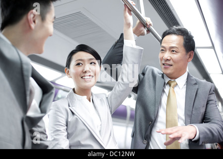 Business persons talking in subway train Stock Photo