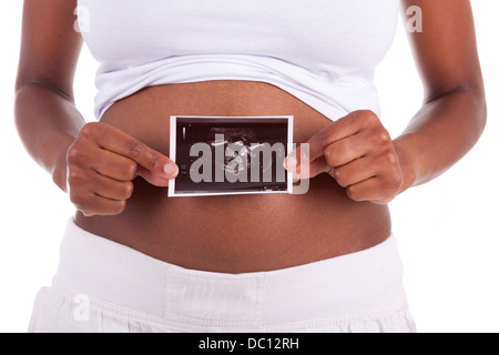 Young pregnant black woman holding an ultrasound picture in front of her belly , isolated on white background - African people