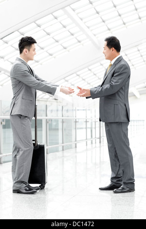 Business associates exchanging business card in airport lobby Stock Photo