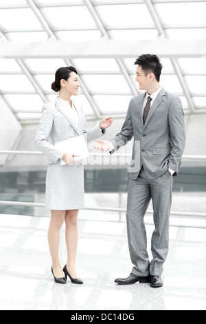 Business colleagues with digital tablet talking in airport lobby Stock Photo