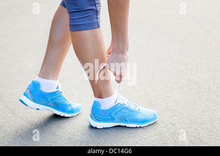 Closeup of Young Woman Tying Sports Shoe - concept image Stock Photo