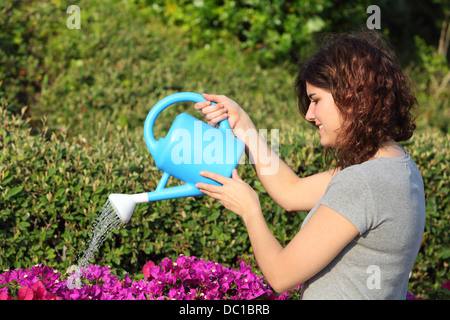 Beautiful woman watering flowers with a watering can in the garden Stock Photo