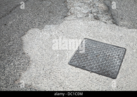 Square metal hatch on asphalt road Stock Photo