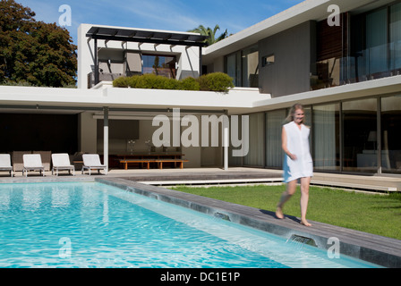 Woman walking along luxury swimming pool Stock Photo