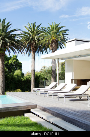 Lounge chairs poolside of modern house Stock Photo