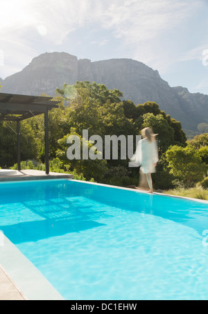 Woman walking along swimming pool Stock Photo