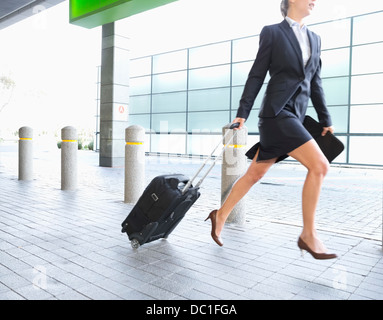 Businesswoman running with suitcase Stock Photo