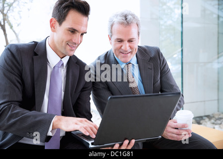 Businessmen drinking coffee and sharing laptop Stock Photo