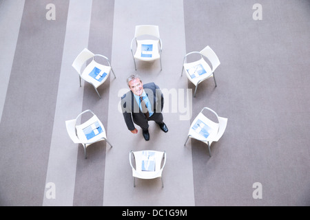 High angle portrait of smiling businessman at center of chairs in circle Stock Photo