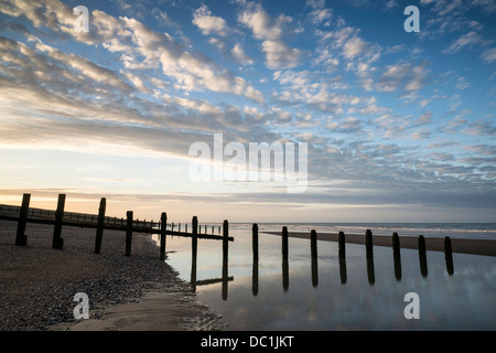 Beautiful sunrise reflected in low tide water pools on beach landscape Stock Photo