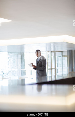 Businessman using digital tablet in lobby Stock Photo